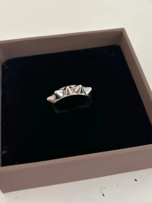 Silvrig ring med nitar - Cool och trendig ring i silver metall från Edblad med fem nitar runt ovansidan. Märkningen på insidan visar storlek 18.50🩷