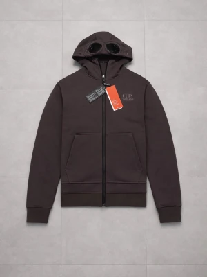 CP Company Hoodie - Mörkbrun hoodie från C.P. Company med dragkedja framtill och ikoniska glasögon i huvan. Stora fickor på magen och diskret logga på bröstet. Tillverkad i mjukt bomullsmaterial och har ribbade muddar vid ärmar och nederkant.