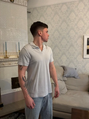 Grå piké t-shirt med krage - Säljer en stilren grå piké t-shirt med klassisk krage och korta ärmar. T-shirten har en enkel och clean look som passar perfekt till jeans eller shorts. Materialet känns mjukt och bekvämt mot huden. Perfekt för dig som gillar en avslappnad men ändå snygg stil. Använd 1-2 gnr!