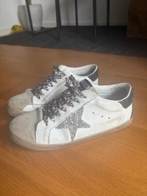 Golden Goose superstars - Golden Goose superstars vita med silverglittrig stjärna och leopard snören, skorna är i bra skick och är i storlek 39. Endast skor medföljer i köpet!