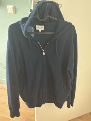 Mörkblå hoodie från ONEWear Sweden - Mysig mörkblå hoodie från ONEWear Sweden i storlek XS. Tröjan har dragkedja framtill, två fickor och en stor huva. Tillverkad i mjukt material som känns skönt mot huden. Perfekt för en avslappnad och chill stil.