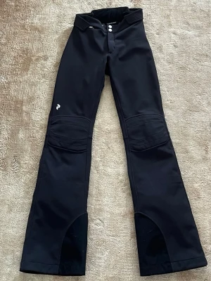 Svarta skidbyxor från Peak Performance - Jättefina svarta skidbyxor med utsvängda ben från Peak Performance. Endast använda 2 säsonger så i jättefint skick. Modellen är extra long, med innerbenslängd på 82 cm.