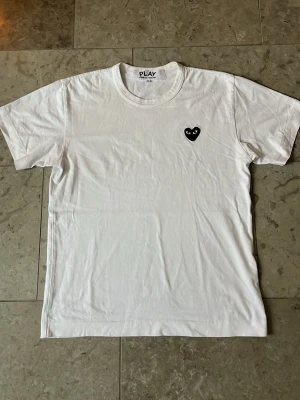 Vit Cdg tshirt - Säljer en klassisk vit t-shirt från Cdg Play | Storlek S | Nästan nyskick, har används väldigt skonsamt | Hör av er vid fler frågor!🙏