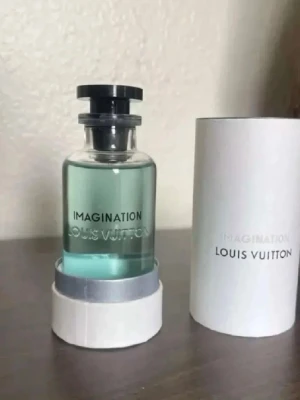 Louis Vuitton Imagination parfym - Lyxig parfym från Louis Vuitton, modellen Imagination. Flaskan är genomskinlig med svart lock och har en stilren, modern design. Parfymen har en ljusblå ton och kommer i en elegant vit förpackning med silverdetaljer. Perfekt för dig som gillar exklusiva dofter.