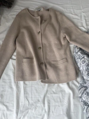 Beige stickad cardigan jacka Hampton Republic - Säljer en beige stickad cardigan jacka/kofta  från Hampton Republic i storlek M. Jackan/koftan  har rund hals, tre knappar framtill och två fickor. Perfekt för dig som gillar klassisk och enkel stil med en chill vibe.