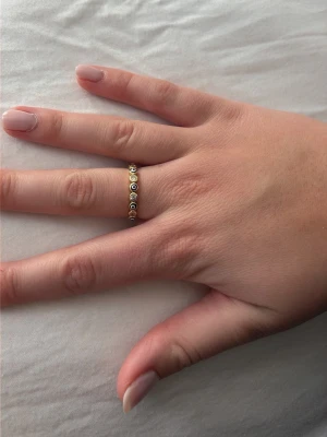 Guldfärgad ring med små pärlor - Säljer en snygg guldfärgad ring dekorerad runt hela ringen. Ringen har en tunn och elegant design som ger en trendig och stilren look. Perfekt för dig som gillar detaljer och vill addera något extra till din outfit. Guldpleterad silverring. Aldrig använd. 