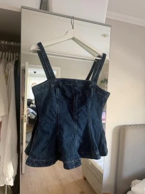 Mörkblå jeans korsettopp - Säljer en snygg mörkblå jeanstop med breda axelband och figurnära passform. Toppen har dragkedja i ryggen och lätt utsvängd nederkant. 💞