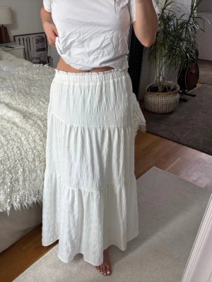 Vit långkjol  - Lång volangkjol, köpt på en marknad. Troligen storlek S. Bra längd på mig som är 168cm.