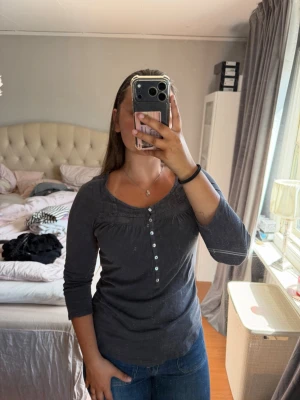 Grå långärmad blus från H&M - Säljer en grå långärmad blus från H&M med knappar framtill och fina söm-detaljer vid bysten. Blusen har en rundad halsringning och knappar på ärmarna om man vill vika upp dom🩶 Tunn i materialet