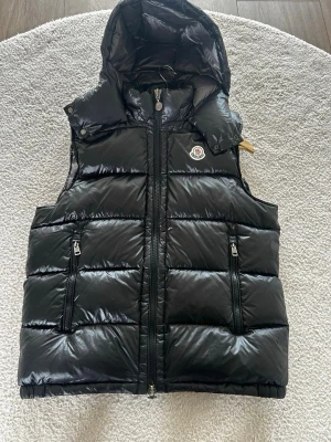 Svart väst  - En svart och stilig väst i storlek 2 (Moncler storlek), perfekt för sommaren, alla taggar medföljer. Hör av er vid minsta lilla