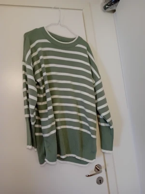 Grön och vit randig oversized tröja - Snygg oversized tröja i grönt och vitt med horisontella ränder. Tröjan har rund halsringning, långa ärmar och bred ribbad mudd vid ärmslut och nederkant. Perfekt för en avslappnad och trendig look.