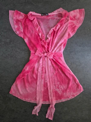 Rosa meshblus med volang  - Supersnygg vintage 2000s rosa meshblus V-ringad med volangdetaljer och ett knytband framtill.