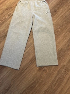 ADWYSD mjukisbyxor - Gråa mjukisbyxor från ADWYSD i rak modell med resår i midjan och sidofickor. På framsidan finns ett litet tryck och på bakfickan står det 'always do what you should'. Perfekta för en avslappnad stil. Mjukt material..