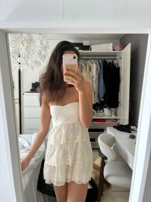 Spetsklänning - Säljer denna underbara crémevita sommarklänning! Den är bandeau med tre lager spets. Den är i strl 38 som syns på sista bilden men skulle kalla den mer för en 36💕💕