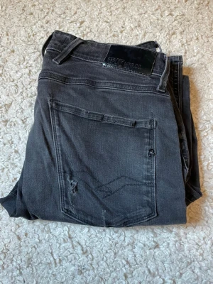 Svarta jeans från Replay - Snygga svarta jeans från Replay med klassisk femficksdesign och diskreta slitningar på bakfickan. Jeansen har en svart läderpatch med Replay-logga bak i midjan. Tillverkade i mjuk denim med en modern passform.