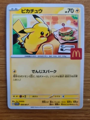 Pokémon Pikachu McDonald's Promo-kort - Unikt samlarkort med Pikachu från Pokémon, McDonald's promo. Kortet har en färgglad framsida med Pikachu vid ett bord med hamburgare och dryck. Japansk text och McDonald's-logga. Baksidan har klassisk Pokémon-design. Perfekt för samlare!