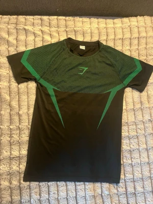 Gymshark compression shirt - En svart/grön Gymshark compression shirt. Den är inte väldigt bra skicka med ingen tecken på slitage. 