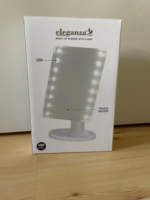 Eleganza sminkspegel med LED-belysning - Sminkspegel från Eleganza med inbyggd LED-belysning runt spegeln. Spegeln är rektangulär och står på en rund fot. Touch-funktion för att slå på och av ljuset. Perfekt för smink och styling.