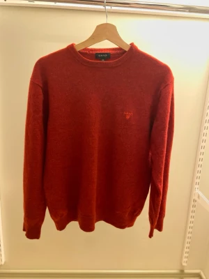 Röd stickad tröja från GANT - Röd stickad tröja från GANT med rund halsringning och diskret broderad logga på bröstet. Tröjan har långa ärmar och ribbade muddar vid ärmslut och nederkant. Perfekt för dig som gillar klassisk och stilren design. Det står att stor leken är XXL men är egentligen XS-S. (NY PRIS 1200kr). Va inte rädda för att fråga! Pris kan diskuteras!!