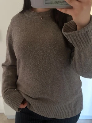 Beige stickad tröja med rund hals - Mysig beige stickad tröja med rund halsringning och ribbade muddar vid ärmslut och nederkant. Tröjan har en avslappnad passform och är perfekt för lager-på-lager. Passar till både jeans och kostymbyxor.