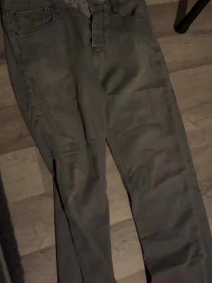 Gråa jeans från Emporio Armani - Snygga gråa jeans från Emporio Armani med klassisk femficksdesign och raka ben. Jeansen har en diskret logga på fickan och är tillverkade i ett mjukt denimtyg som ger en avslappnad men stilren look. Äkta med Scan som tar dig in i Armanis hemsida. Nästan helt nya använda 4-5 gånger. Riktiga bra jeans för billigt pris. 