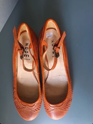 Terracotta ballerinaskor från Zoom Shoes - Säljer ett par terracottafärgade ballerinaskor / Mary Jane modell från Zoom Shoes. Skorna är i skinn med rund tå och dekorativa sömmar framtill. Skorna har en justerbar rem med spänne över vristen för extra bra passform och liten klack och gummisula för bekvämlighet. 