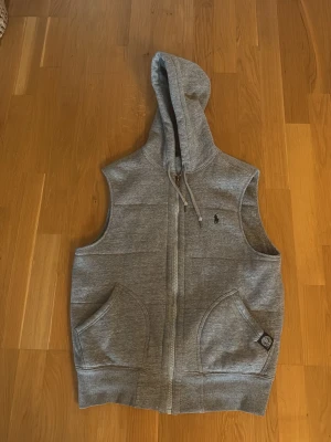 Grå huvväst från Polo Ralph Lauren - Snygg grå väst med huva från Polo Ralph Lauren. Pris går att 