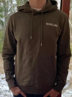 Olivgrön hoodie från Helmut Lang - Snygg olivgrön hoodie från Helmut Lang med vit logga på bröstet. Storlek L men sitter som en M. Skick 9/10. Hör av er vid frågor🙏