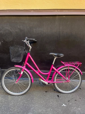 Rosa occano cykel  - Säljer en rosa cykel, korgen är lite bucklig, osäker på om lampan funkar, stöd saknas. Cykeln har 3 olika växlar. Nypris 3 500 kr, kan hämtas i St Eriksplan. Storlek 38, passar personer som är ca 150-165 cm. Sadel går att justera. 