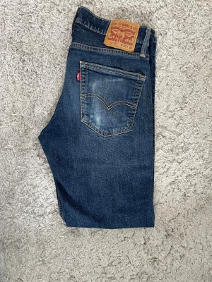 Mörkblå jeans från Levi's 514 - Klassiska mörkblå jeans från Levi's med rak passform och femficksmodell. W30 L30, 514, priset är inte hugget i sten! Jeansen har en tidlös look med sömmar och knappgylf. Tillverkade i slitstark denim som passar perfekt till alla tillfällen. Riktigt snygg fade på backfickan.
