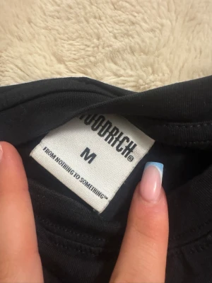 Svart långärmad topp från Hoodrich - Svart långärmad topp från Hoodrich med vit logga broderad på bröstet. Enkel och stilren design med rund halsringning. Perfekt att matcha med jeans eller kjol för en clean look.