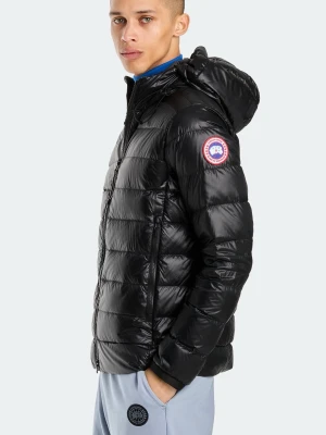 Svart dunjacka från Canada Goose - Snygg svart dunjacka från Canada Goose med glansig finish, huva och dragkedja framtill. Jackan har märkets klassiska logga på ärmen och invändiga axelband med Canada Goose-tryck. Perfekt för kalla dagar.