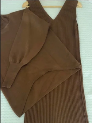 Brun ribbad långärmad klänning  - Snygg brun långärmad topp med ribbade detaljer och rund hals. Toppen har en loose passform och är tillverkad i ett mjukt, stretchigt material som känns skönt mot huden. co ord kläning med både sweatshirt och ribbad klänning. den är i onesize och är ganska stretchig så den passar s-L