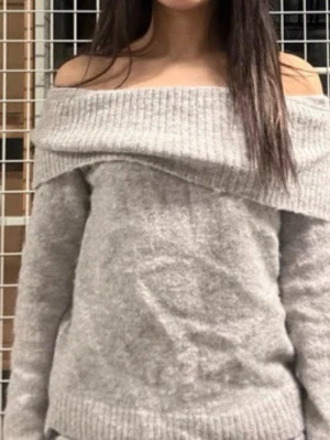 Ljusgrå off shoulder stickad tröja från Gina Tricot - Säljer en ljusgrå stickad tröja med bred off shoulder-krage och långa ärmar. Tröjan har en avslappnad passform och ribbstickade detaljer vid krage, ärmslut och nederkant. Perfekt för dig som gillar en trendig och mysig look.