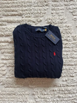 Mörkblå kabelstickad tröja Ralph Lauren - Kabelstickad mörkblå tröja från Polo Ralph Lauren, den är helt ny och aldrig använd med lappen kvar. Den är storlek L och har tvär myssigt material. Skriv i DM om det är nått du undrar över kan också gå ner i pris vid snabbt köp. 🥂