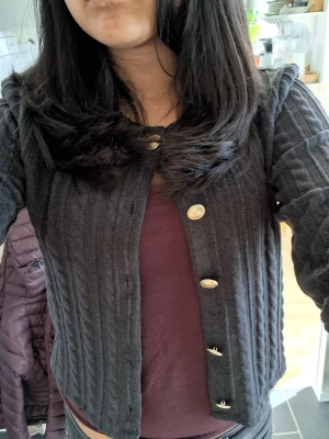 Mörkgrå kofta - Hejj jag säljer en mörkgrå/svart kofta med guldfärgade knappar framtill. Koftan har rund halsringning och lång ärm. Helt ny, aldrig andvänd och lappen är kvar. Den köptes online på den "portugisiska" H&M därför har den inget pris på lappen.