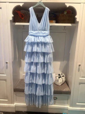 Balklänning från bubbelroom -  långklänning i ljusblått med flera lager volanger och v-ringning. Har sytt upp vid axlarna så v-ringningen är inte lika djup. Perfekt för bal eller festliga tillfällen. Klänningen är ifårn bubbelroom storlek 36, Jag är 169 och den va lite lång men passar om man vill ha klackar på sig. Har använt den en gång🥰