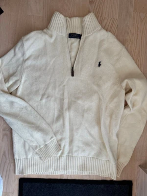 Krämvit stickad tröja från Polo Ralph Lauren - Säljer en kräm vit quarter eller half zip från Polo Ralph Lauren i storlek Medium. Den är självklart äkta. Skickar oftast inom ett dygn.   Den är väl använd men har inga större defekter som hål eller så. Väldigt lite nopprig.   Pris kan diskuteras vid snabb affär!  Köp gärna bundle för att spara på frakt!  Half-zip halfzip quarterzip quarter-zip
