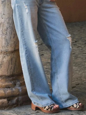 Ljusblåa vida jeans med slitningar - Säljer ett par ljusblåa jeans med bred passform och slitna detaljer på benen. Jeansen har klassisk femficksdesign och hög midja. Perfekta för en avslappnad och trendig look. Materialet är denim i bomull. Helt slutsålda och de är i nyskick, aldrig använda. Nypris 700kr