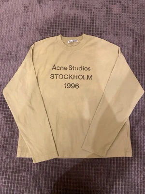 Grön långärmad t-shirt Acne Studios - Snygg grön långärmad t-shirt från Acne Studios med tryck 'STOCKHOLM 1996' på bröstet. Klassisk rund halsringning och relaxed fit, perfekt för en stilren och avslappnad look.