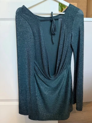 Festklänning  - Glittrig mörkgrön kortklänning med v-ringning baktill. 