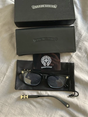 Svarta glasögon med gulddetaljer chrome heart - Snygga svarta glasögon med rektangulär form och coola guldfärgade detaljer på bågarna. Perfekt accessoar för att lyfta din stil och ge en unik touch till din outfit. Köpte från TikTok shop för 470kr med shipping