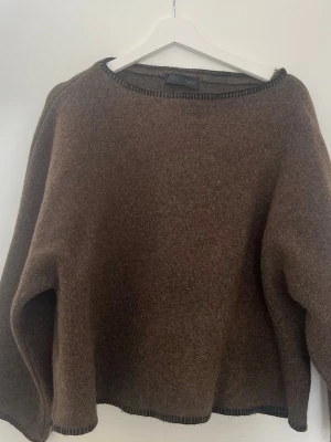 Brun stickad tröja från Zara - Mysig brun stickad tröja från Zara med rund halsringning och dekorativa svarta sömmar vid kanterna. Tröjan har en avslappnad passform och är tillverkad i ett mjukt material som passar perfekt för kyligare dagar.