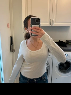 Vit ribbad långärmad topp - Säljer en enkel och stilren vit ribbad topp med lång ärm och rundad urringning. Perfekt att matcha med jeans eller kjol för en clean look. Materialet är mjukt och stretchigt, vilket gör den superbekväm att bära.