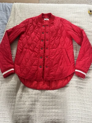 Röd quiltad bomberjacka  - Snygg röd quiltad bomberjacka från Global Funk. Rundad nederkant, tryckknappar framtill, ribbade muddar med vita ränder och två sidofickor. Lagom varm till vår/höst. Storlek xs. Jättebra skick! Aldrig använd! 🤍