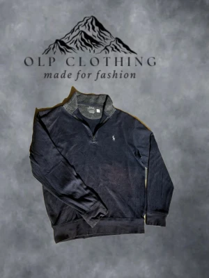 Mörkblå quarter zip från Polo Ralph Lauren - Mörkblå långärmad tröja med quarter zip och grå detaljer vid kragen. Klassisk Polo Ralph Lauren-logga broderad på bröstet. Tröjan är tillverkad i mjukt material och har ribbade muddar vid ärmslut och nederkant. Perfekt för en avslappnad och stilren look.