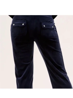 Mörkblå velourbyxor med fickor - Mörkblå mjukisbyxor i velour med raka ben och dragsko i midjan. Byxorna har stora fickor fram och bak, där bakfickorna har lock och knappdetaljer. Perfekta för en chill och avslappnad stil.