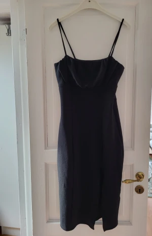 Svart mini klänning  - Svart mini klänning med hourglass form och slit på ena låret✨️ För liten för mig så kan tyvärr inte visa hur den ser ut på men den sträcker sig ungefär ner till halva mitt lår    (är 170cm lång för referens)