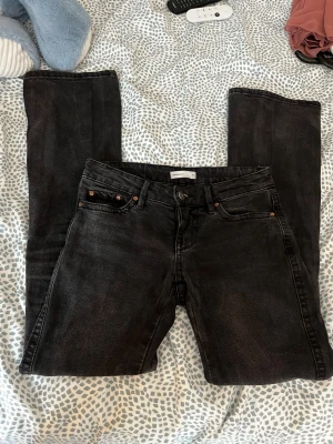 Svarta jeans från Gina tricot - Säljer ett par svarta jeans från Gina tricot med lite bootcut och klassisk femficksmodell. Jeansen har diskreta slitningar och broderade detaljer på bakfickorna.