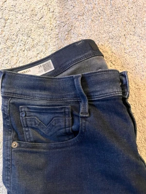 Mörkblå jeans från Replay - Snygga mörkblå jeans från Replay med klassisk femficksdesign och diskreta detaljer. Jeansen är slim i designen och är tillverkade i ett mjukt denimtyg som sitter skönt. Perfekta för dig som gillar stilrena och tidlösa jeans.